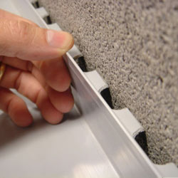 A contractor in Plymouth installing a perimeter drain tile system during a sump pump installation.
