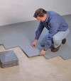 Contractors installing basement subfloor tiles and matting on a concrete basement floor in Benton Harbor, Indiana and Michigan