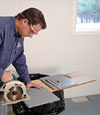installing a waterproof vapor barrier on a basement floor to prepare for basement carpeting in a Mishawaka home