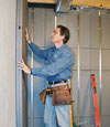 Insulated basement wall panels being placed against a concrete foundation wall in Niles